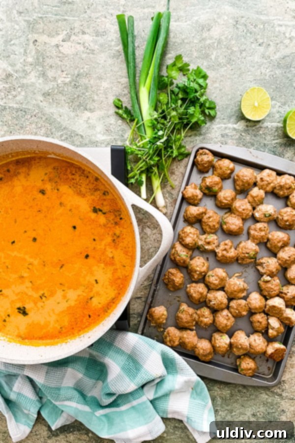 Thai Red Curry Turkey Meatball Delight 6 Baked turkey meatballs simmering in a vibrant red curry sauce in a saucepan.