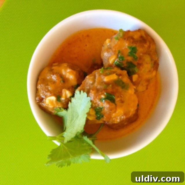 3 meatballs in curry sauce in a bowl.