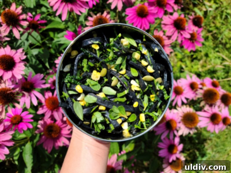 Black pasta salad with colorful vegetables and seeds in stainless steel containers