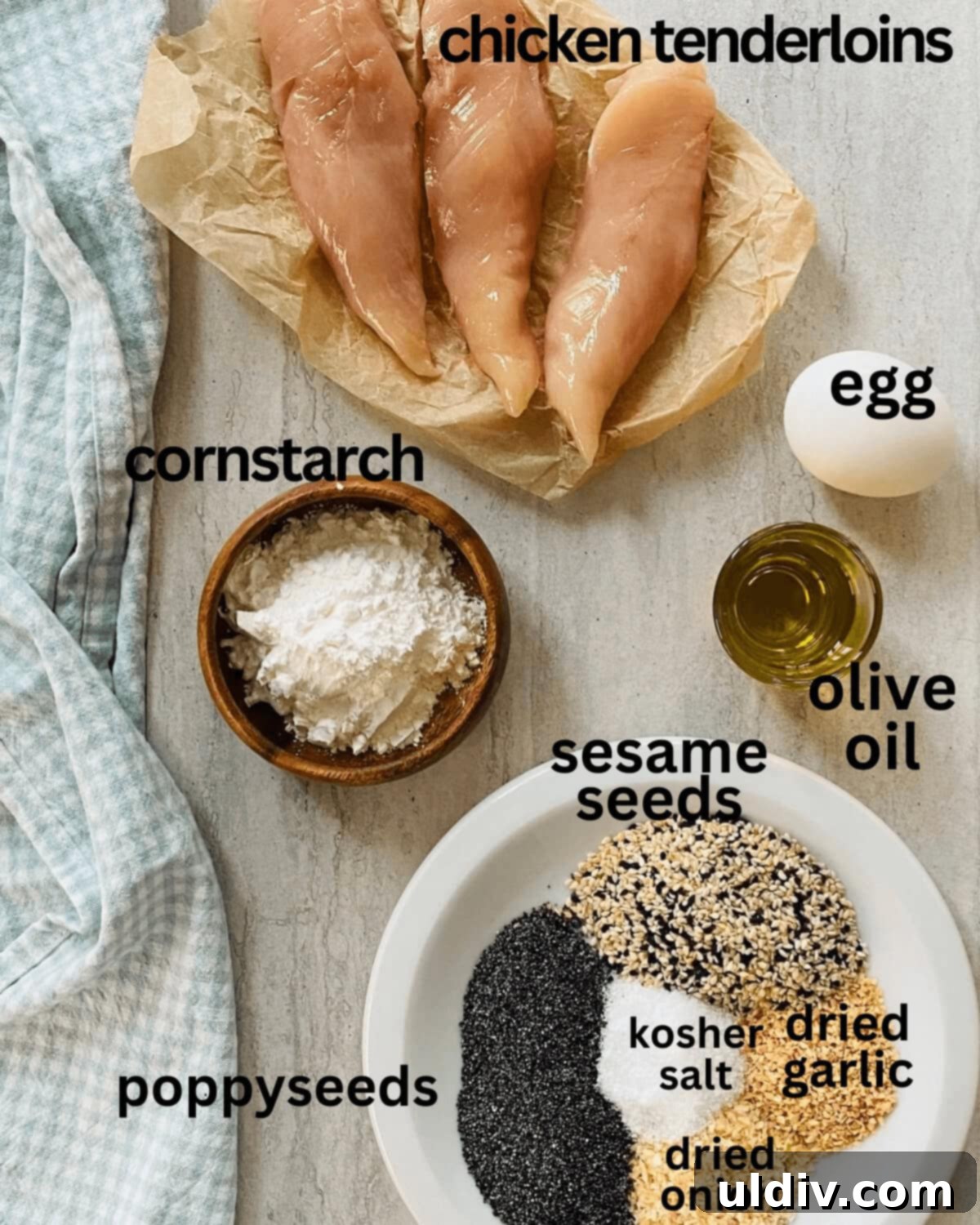 Ultimate Everything Chicken Bites with Fresh Basil Hummus 4 Fresh chicken tenderloins, a bowl of Everything But The Bagel seasoning, an egg, cornstarch, and a bottle of olive oil arranged on a kitchen counter.