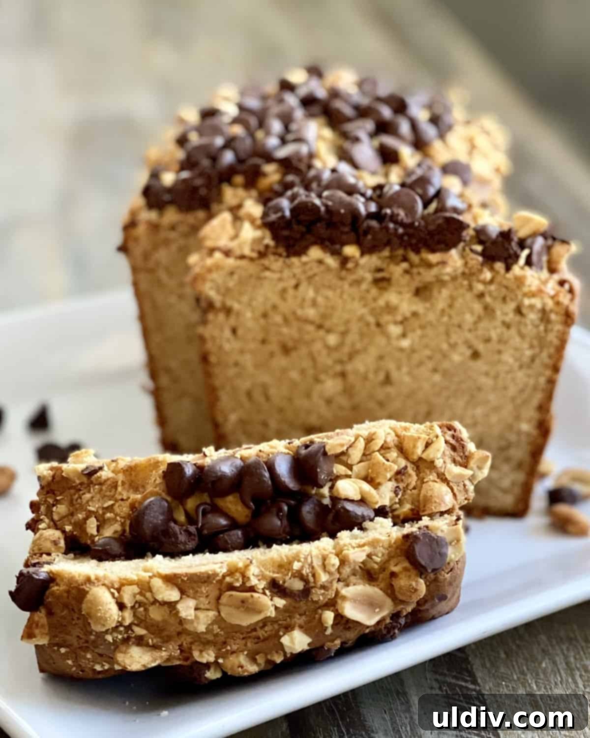 Double Peanut Chocolate Chip Loaf 10 Sliced peanut butter bread topped with peanuts and chocolate chips on a serving platter.