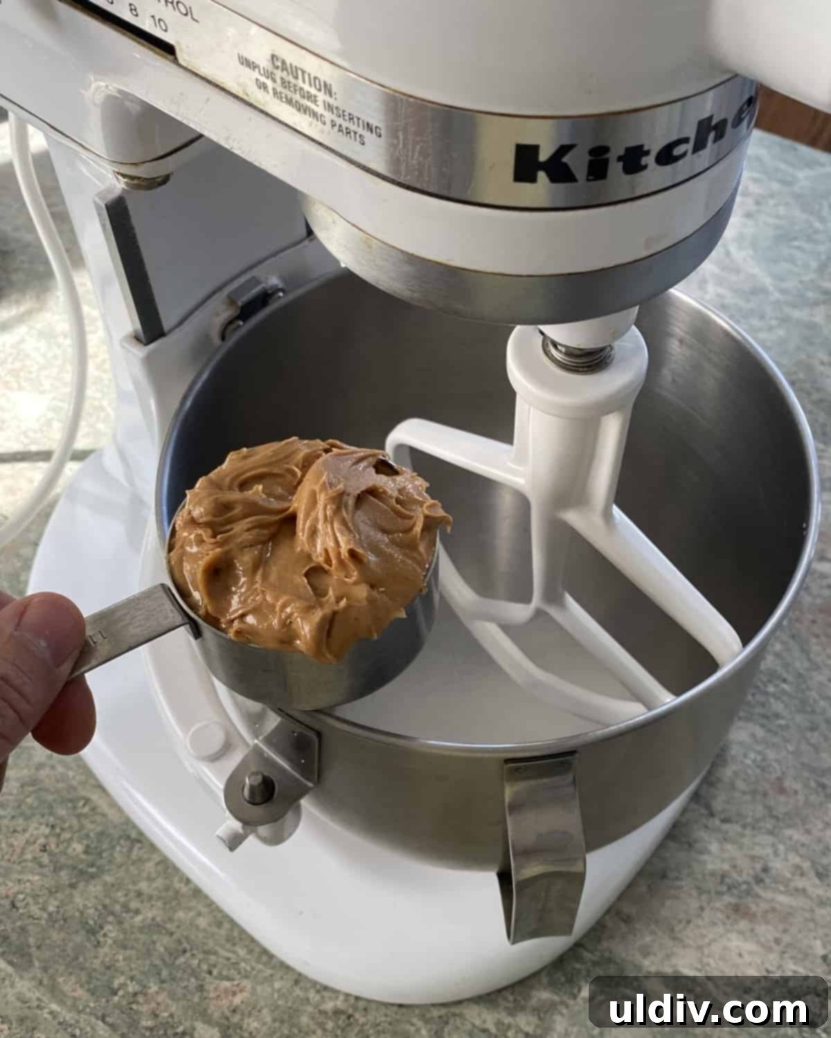 Double Peanut Chocolate Chip Loaf 5 A measuring cup with peanut butter next to a stand mixer.