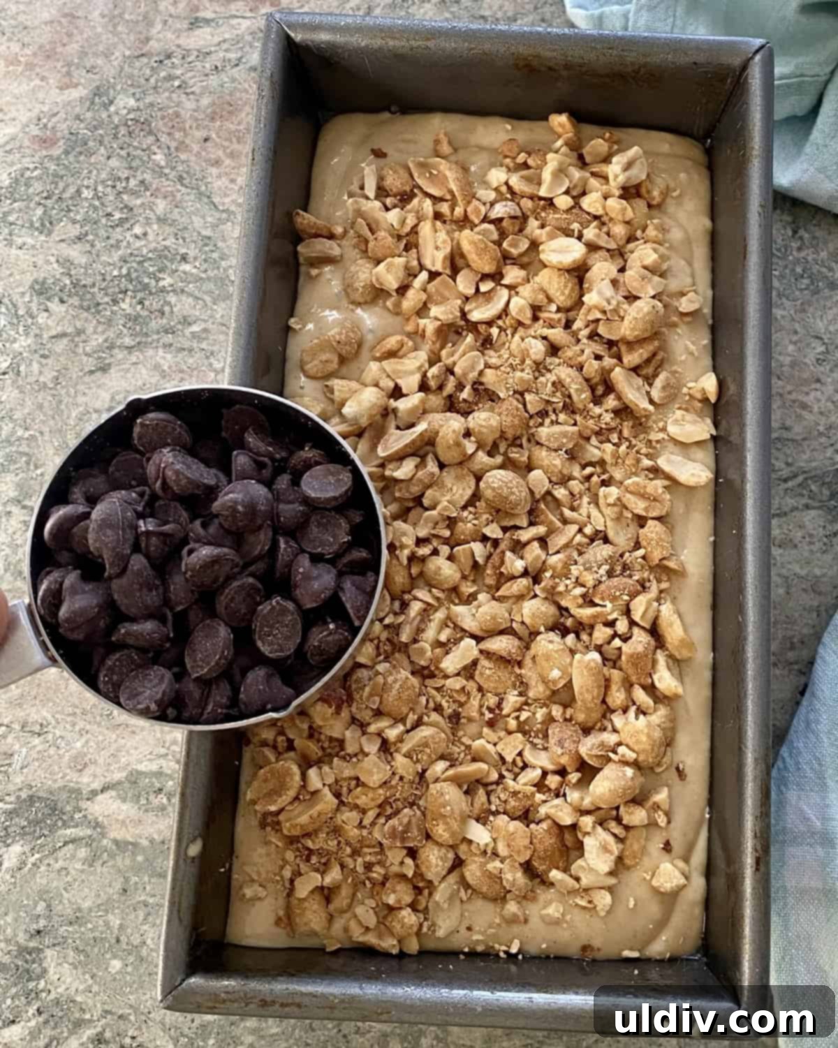 Chocolate Chip Peanut Butter Crunch Bread 7 Sprinkling semi-sweet chocolate chips and chopped peanuts over unbaked peanut butter bread batter in a loaf pan.