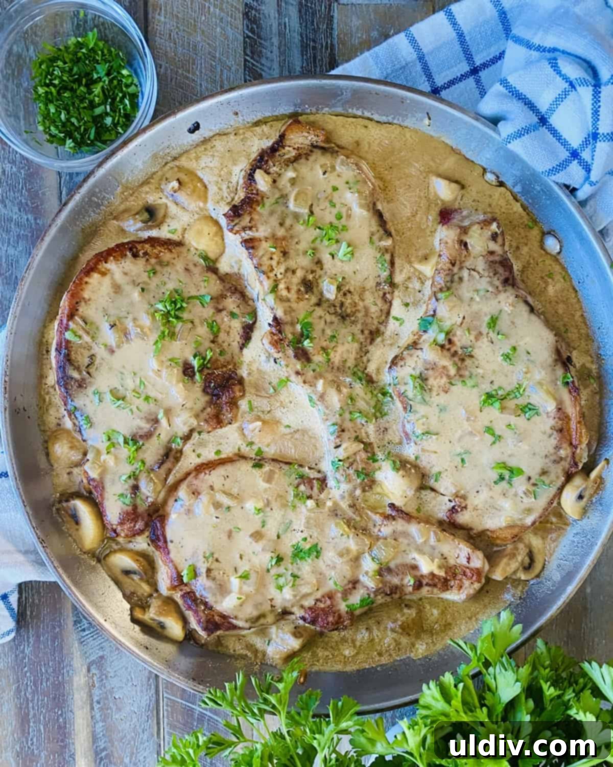Braised Pork Chops with Savory Mushroom Sauce 11 4 pork chops in a creamy mushroom gravy in a pan.