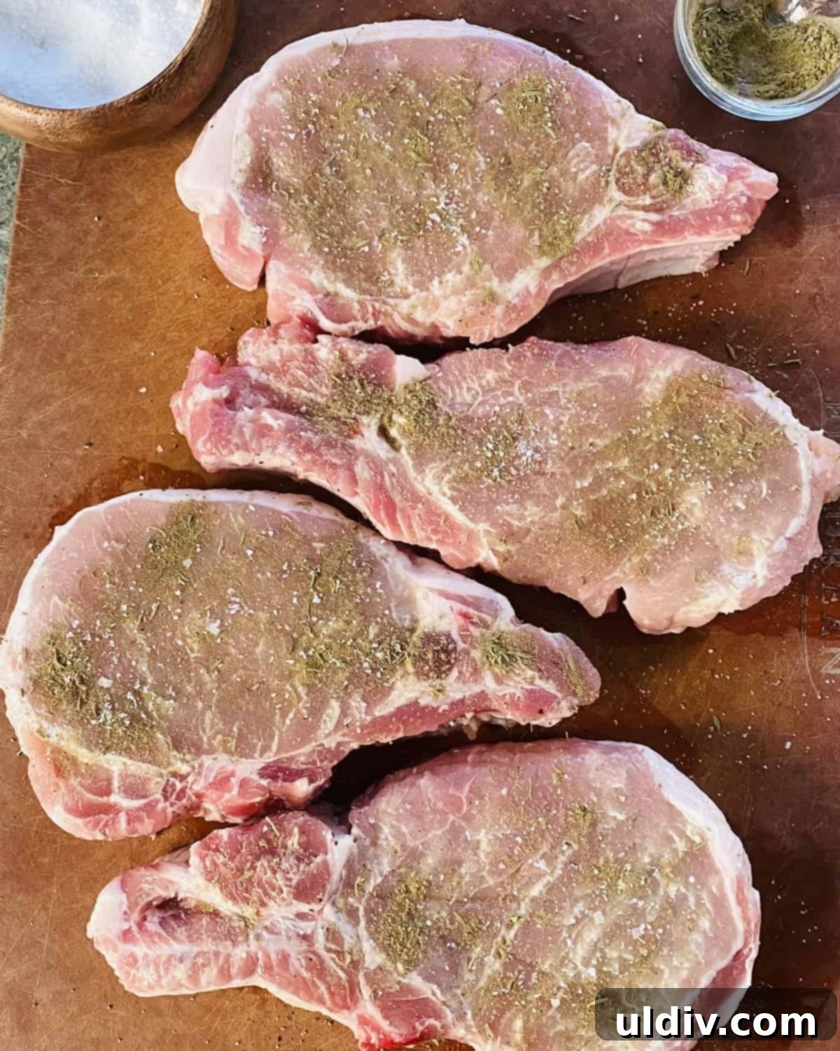 Golden Pork Chops Smothered in Creamy Mushroom Gravy 6 Seasoned pork chops on a cutting board.