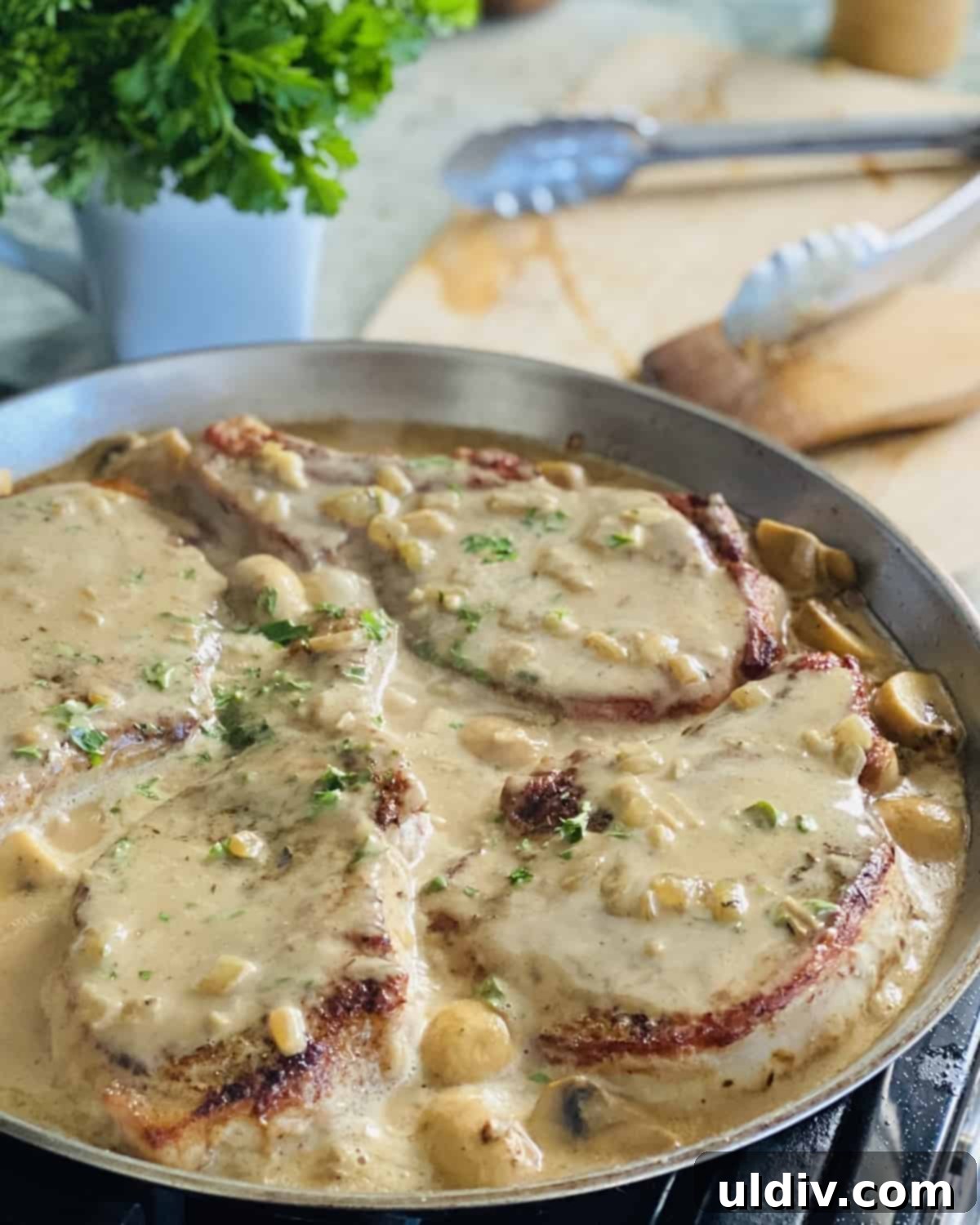 Golden Pork Chops Smothered in Creamy Mushroom Gravy 9 4 bone in pork chops in gravy in a pan.