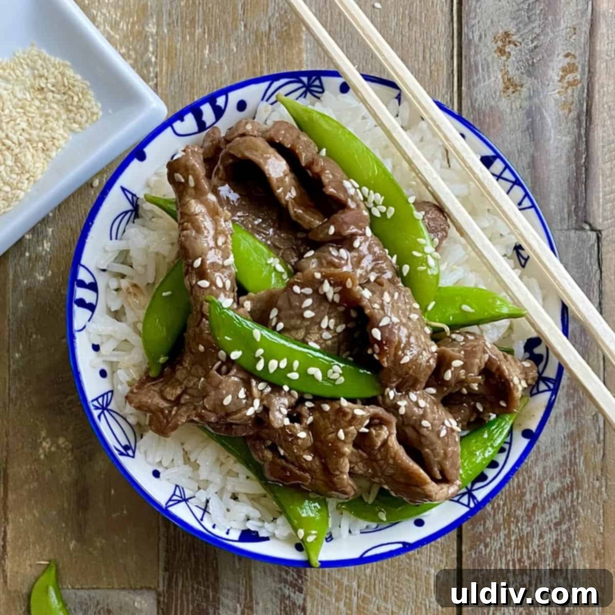 Tender Beef and Crisp Snap Pea Stir Fry 9 A serving of beef stir fry with rice in a bowl, garnished with sesame seeds.