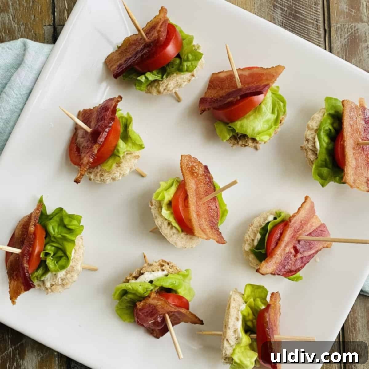 Bite-Sized BLT Sandwiches 12 Toothpicks with bacon, lettuce and tomatoes on a plate.
