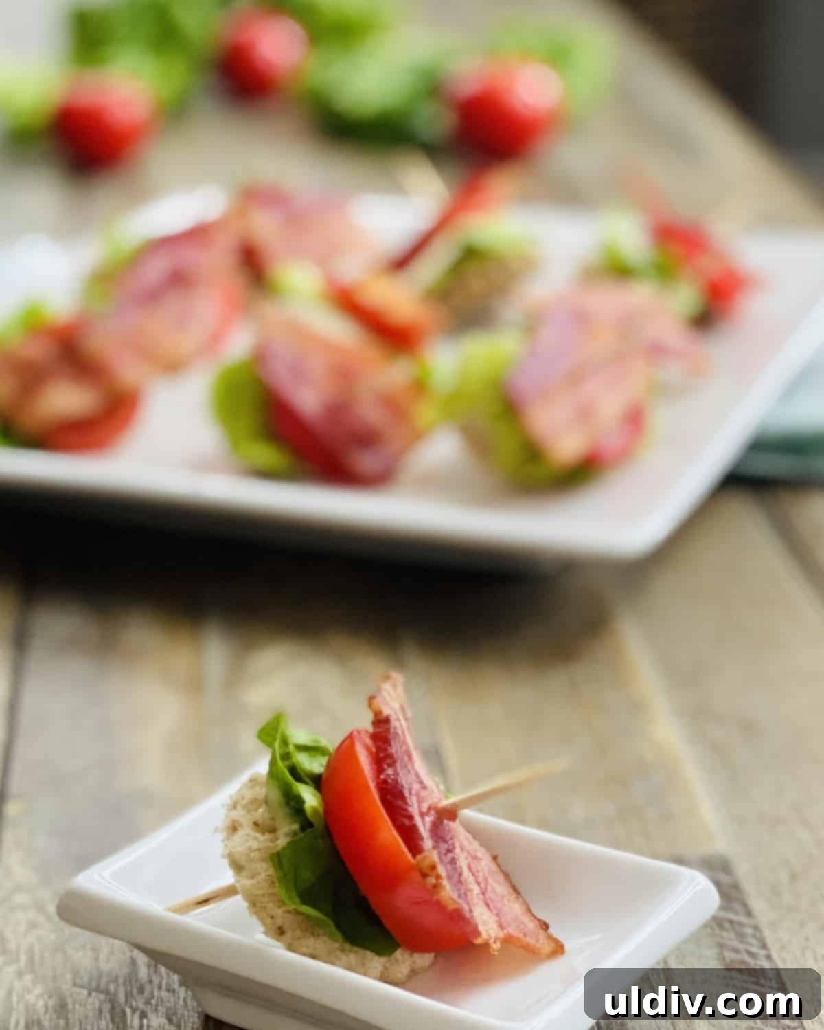 Mini BLT Sandwiches 8 A single toothpick with bacon, lettuce and tomato and a plate.
