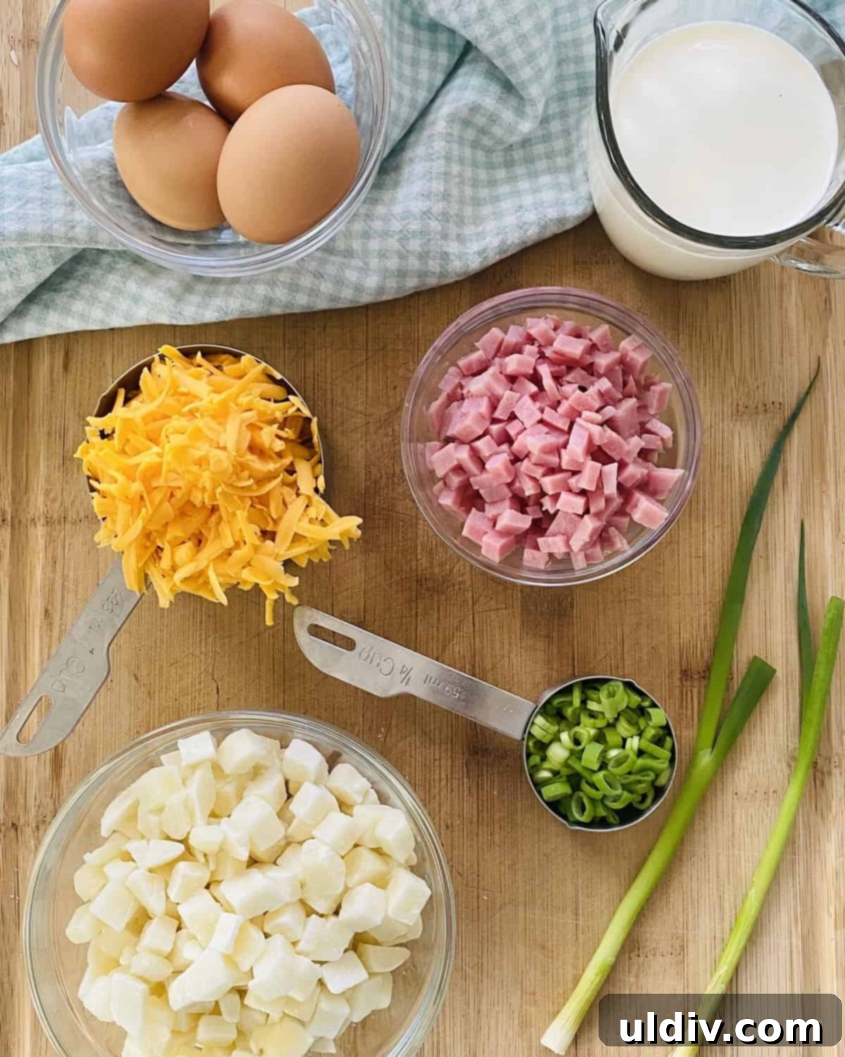 Golden Hash Brown Quiche: Ham and Cheese Delight 4 Eggs, ham, hash browns, heavy cream, cheddar cheese, scallions laid out on a cutting board, ready for preparation.