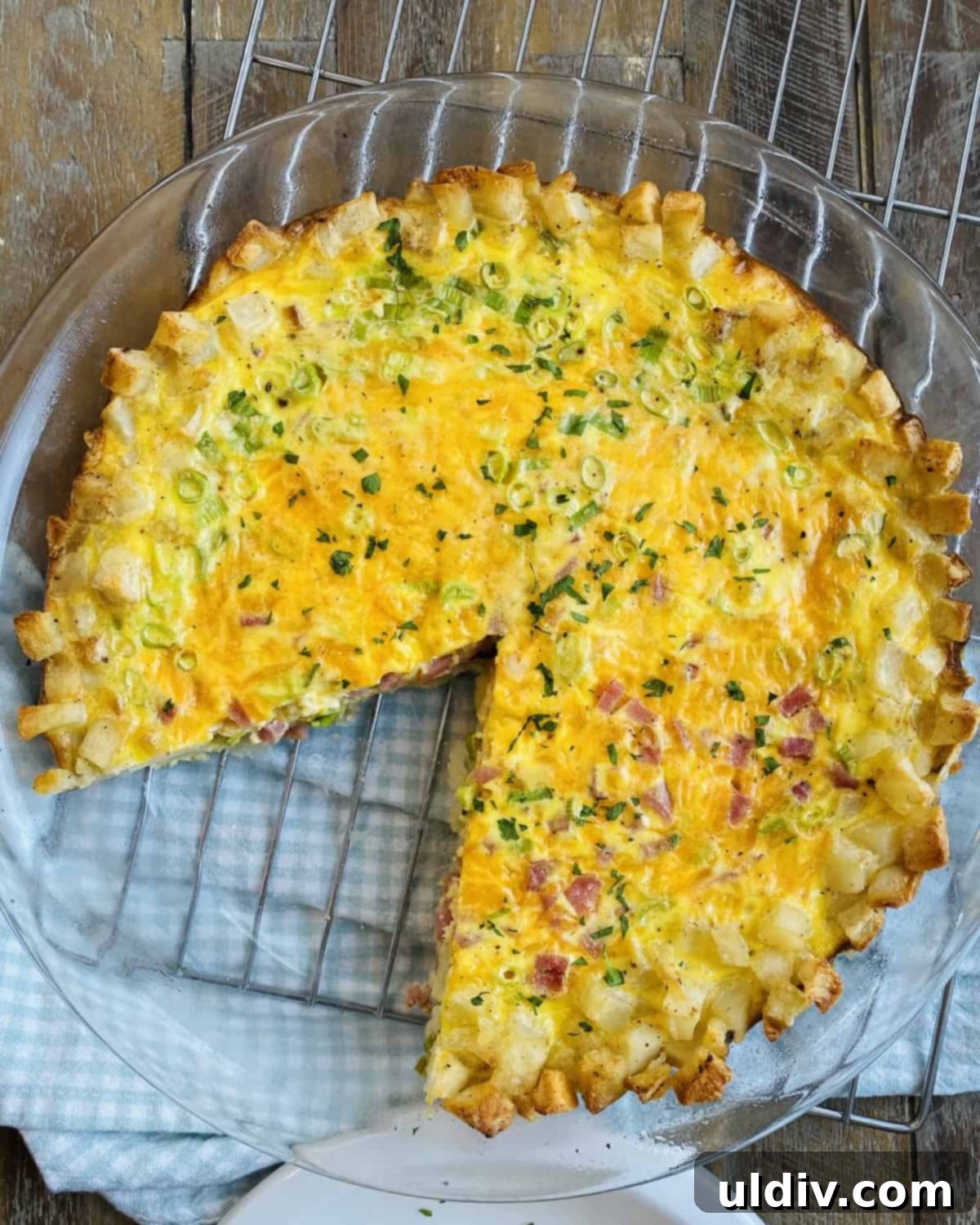 Crispy Hash Brown Quiche with Savory Ham and Cheese 10 A freshly baked hash brown crust quiche with one slice already removed, showcasing its delicious layers and golden, crispy crust, perfect for serving.