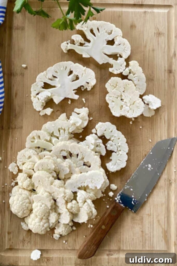 Wholesome Cauliflower Edamame Chickpea Salad 4 slice cauliflower on a cutting board with a knife