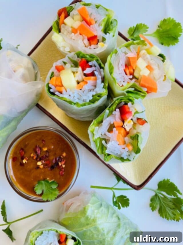 Fresh Vietnamese spring rolls cut in half with a side of creamy peanut sesame dipping sauce.