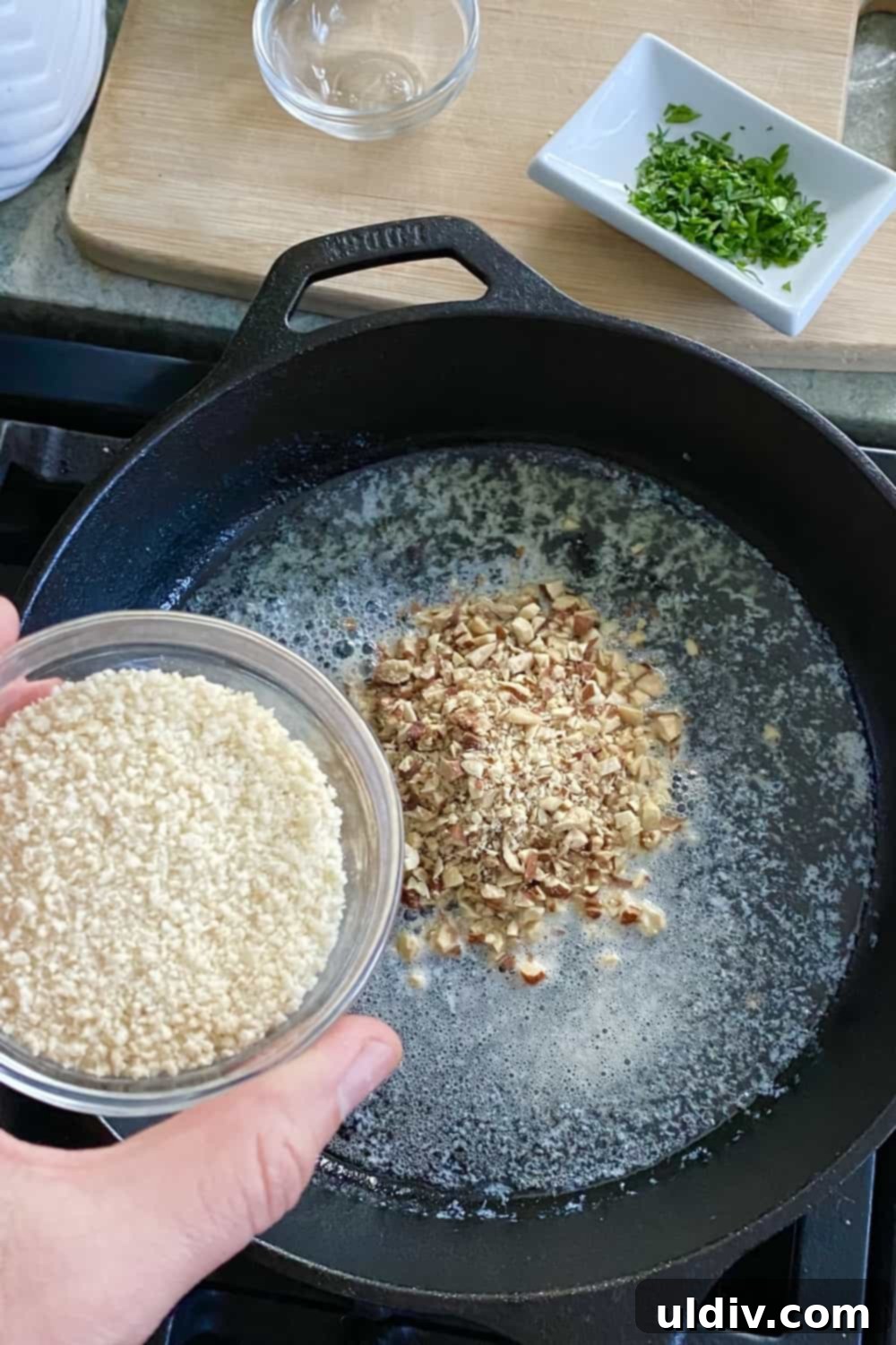 Crispy Pecan Salmon with Tangy Honey Mustard 7 Adding panko to chopped pecans in a cast iron skillet.