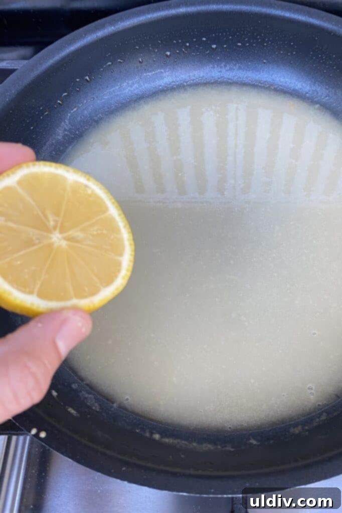 A cook pouring fresh lemon juice into a simmering sauce in a skillet, adding a bright citrus note.