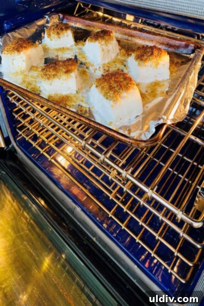 Baked Cod with Herbed Breadcrumbs 7 Golden brown cod fillets with a crispy topping baking in a hot oven, showing the delicious transformation.