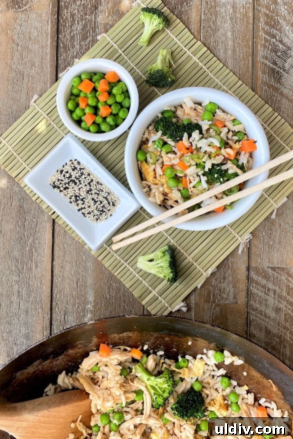 Restaurant-Quality Fried Rice and Chicken at Home 5 overhead photo of a bowl of Asian chicken and rice with chopsticks and sesame seeds
