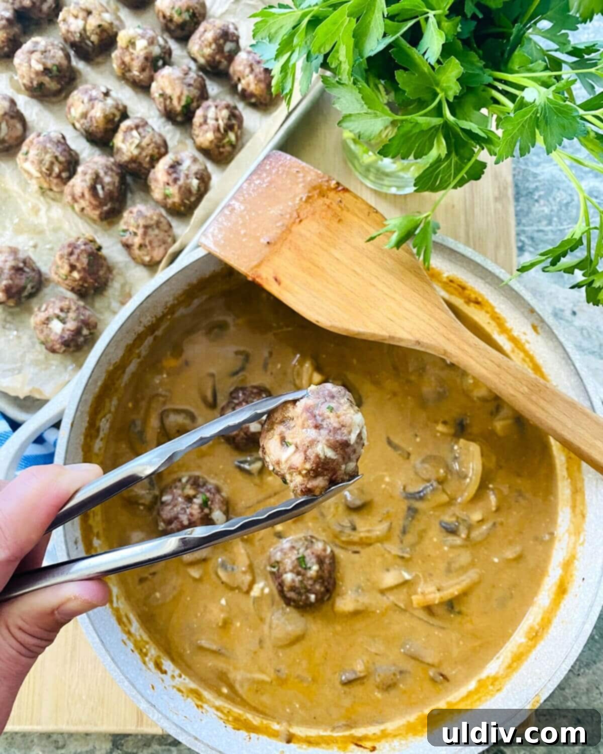 Quick and Easy Meatball Stroganoff 12 Baked meatballs being gently added to the finished creamy stroganoff sauce in a large pan.