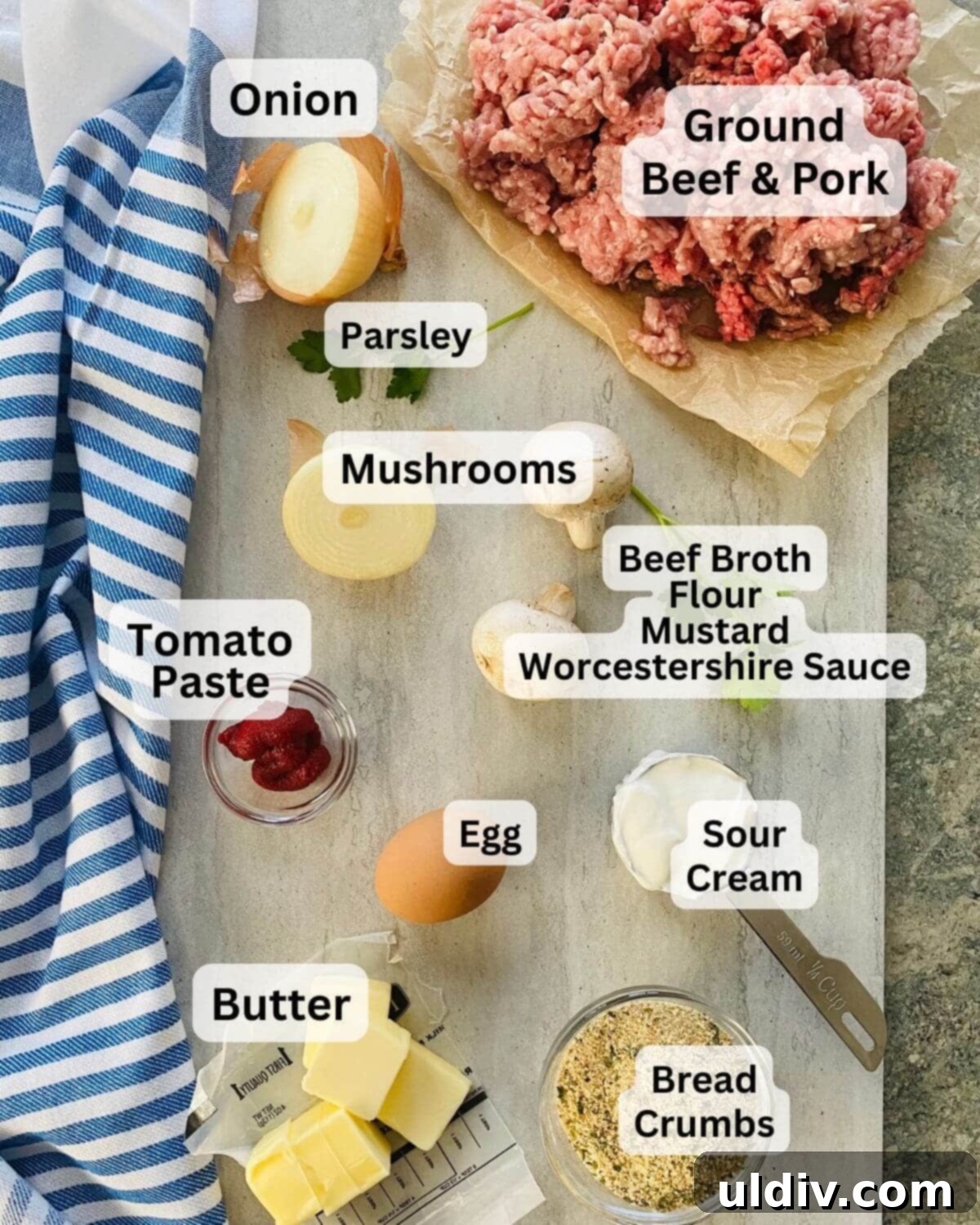 Effortless Homemade Meatball Stroganoff 4 Ground beef and pork, onion, mushrooms, sour cream, parsley, egg, bread crumbs, and butter on a cutting board.