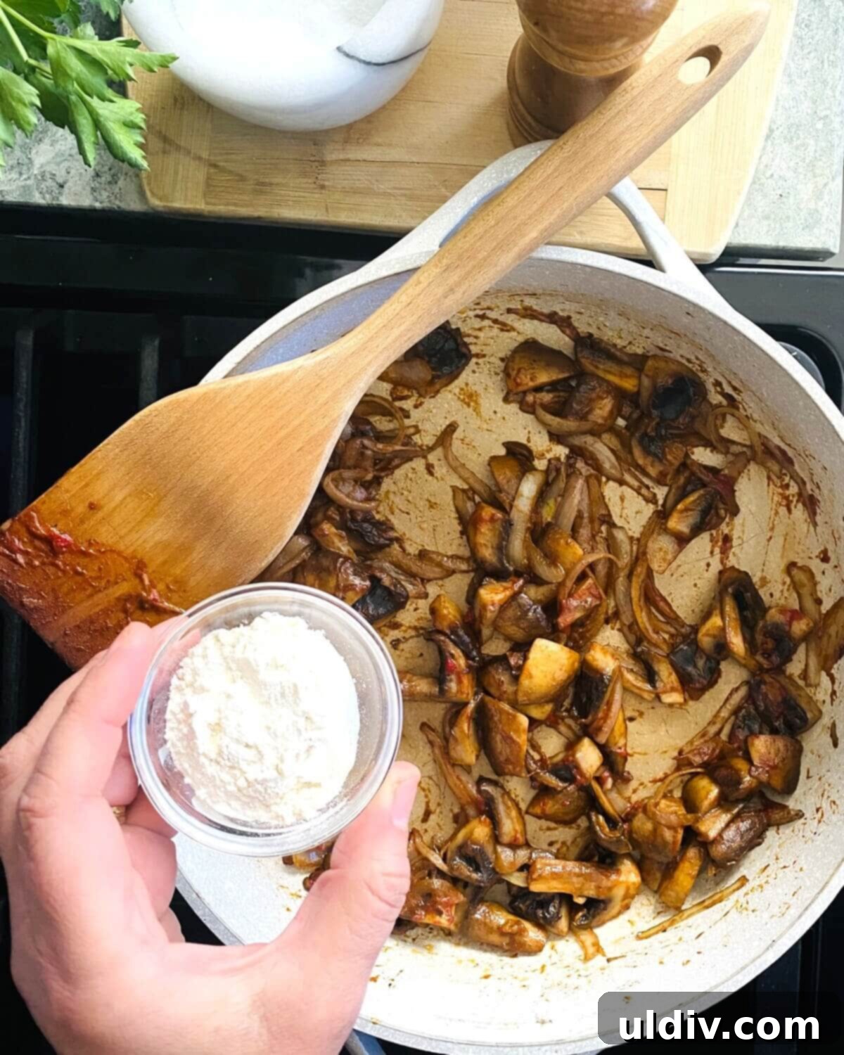Quick and Easy Meatball Stroganoff 10 All-purpose flour being sprinkled evenly over the mushroom and onion mixture in the pan.
