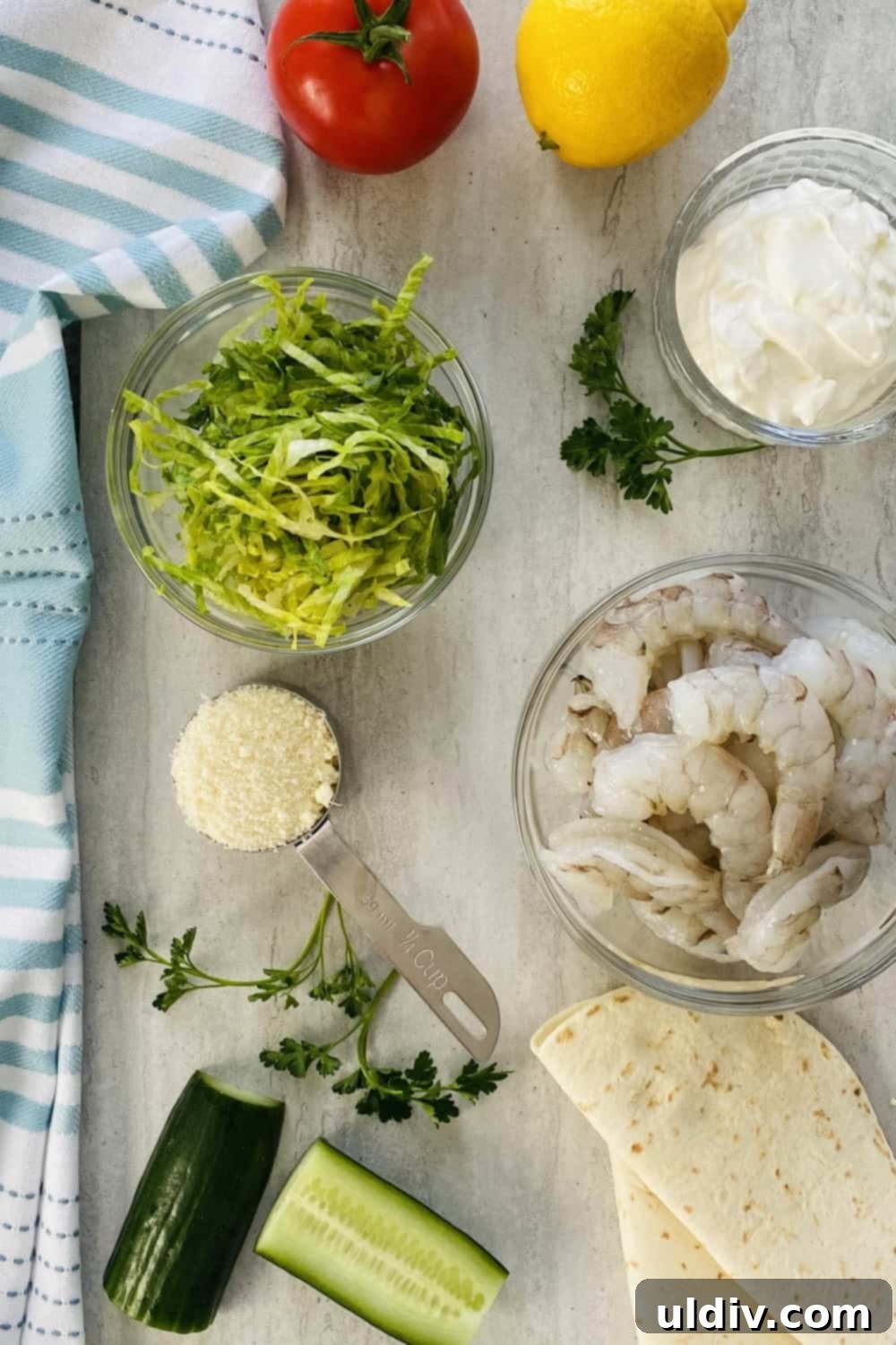 Sun-Kissed Shrimp Tacos with Zesty Tzatziki 3 A vibrant selection of fresh ingredients laid out, including cucumber, lettuce, tomato, raw shrimp, plain yogurt, and Parmesan cheese, ready for making Mediterranean shrimp tacos.