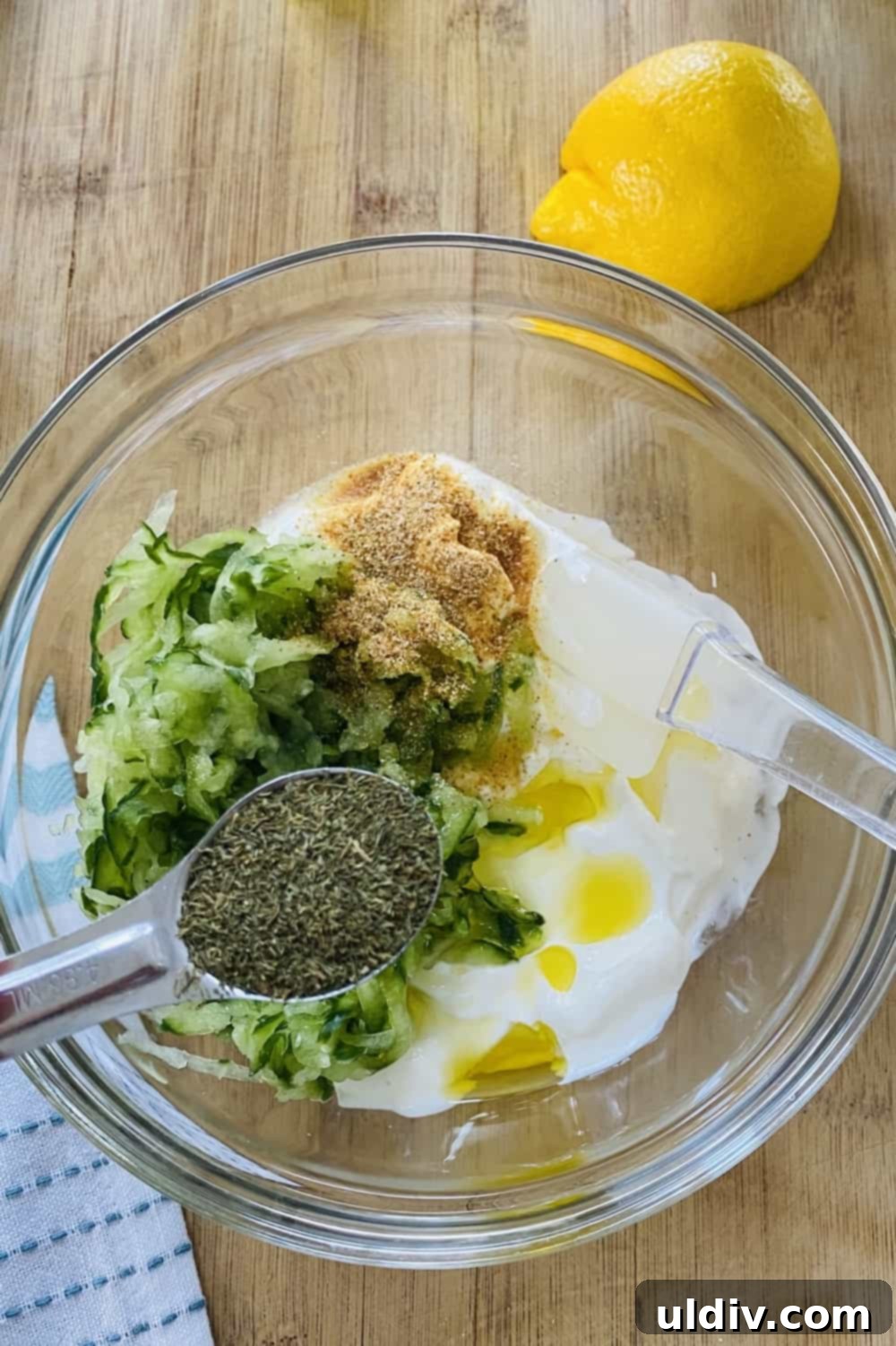 Sun-Kissed Mediterranean Shrimp Tacos with Zesty Tzatziki 6 The process of making tzatziki sauce, showing creamy plain yogurt, finely shredded cucumbers, and a blend of seasonings in a bowl.