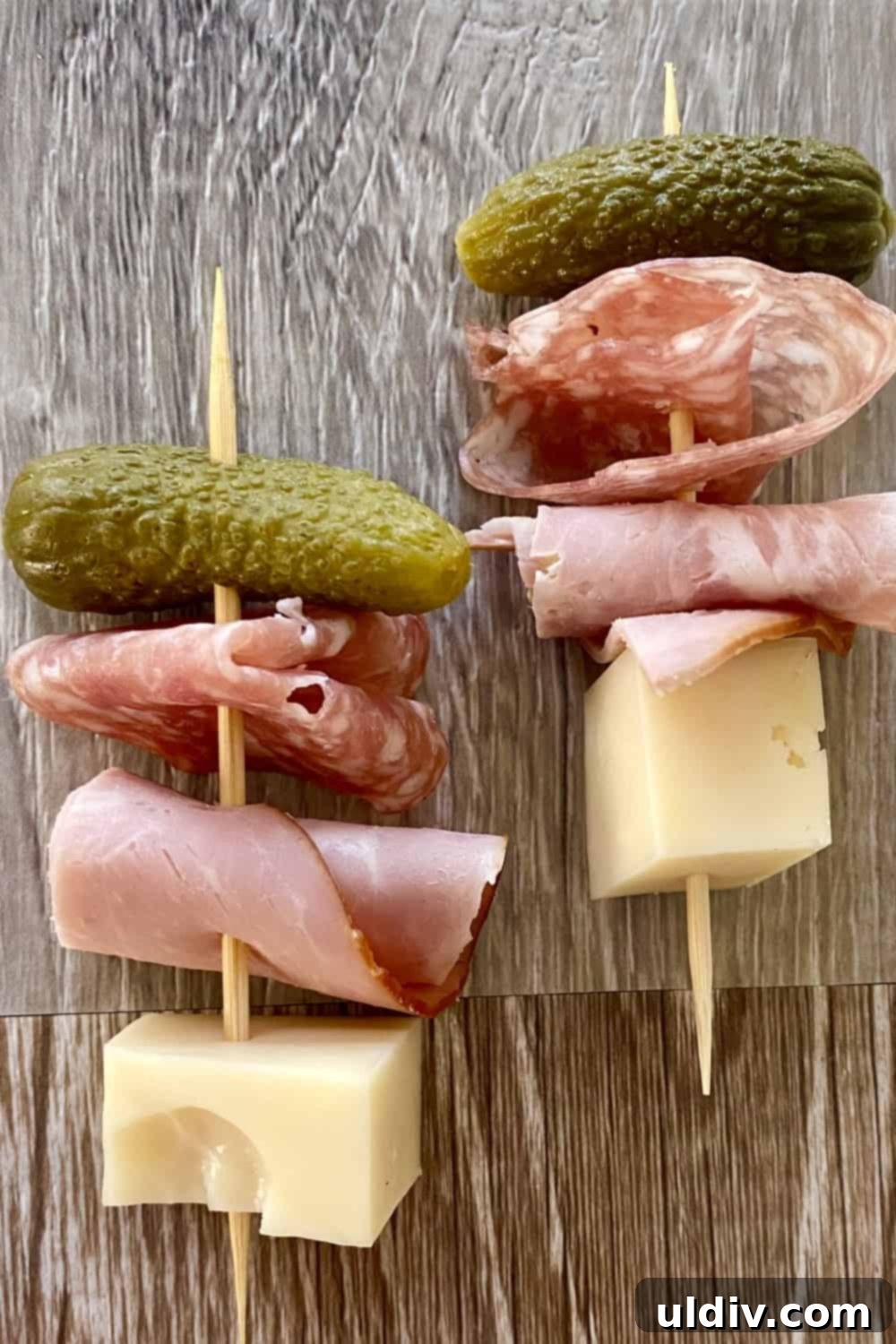 Mini Cuban Sandwich Skewers 5 A toothpick with a cheese cube, ham roll up, salami roll up and a small pickle.