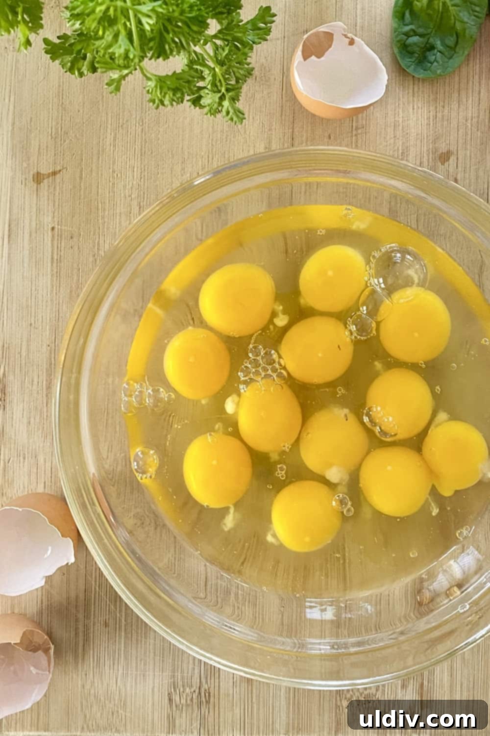 Effortless Baked Frittata 4 A large glass bowl filled with cracked, fresh eggs, ready for whisking.