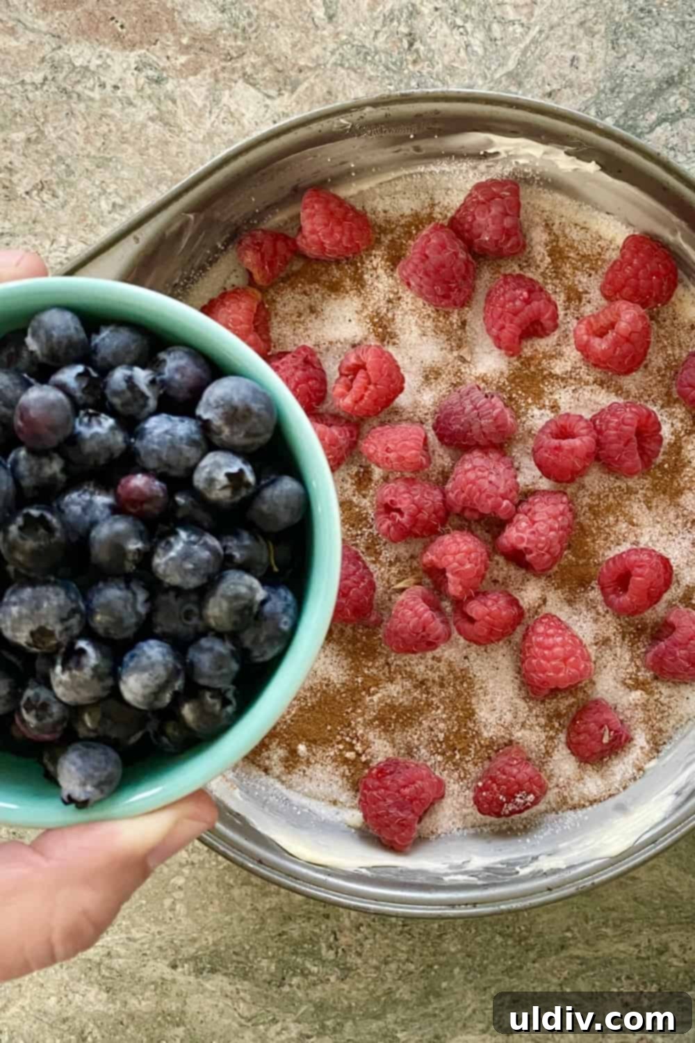 Berry Burst Upside Down Cake 5 Adding blueberries and raspberries to a buttered and sugared cake pan for the upside down cake.