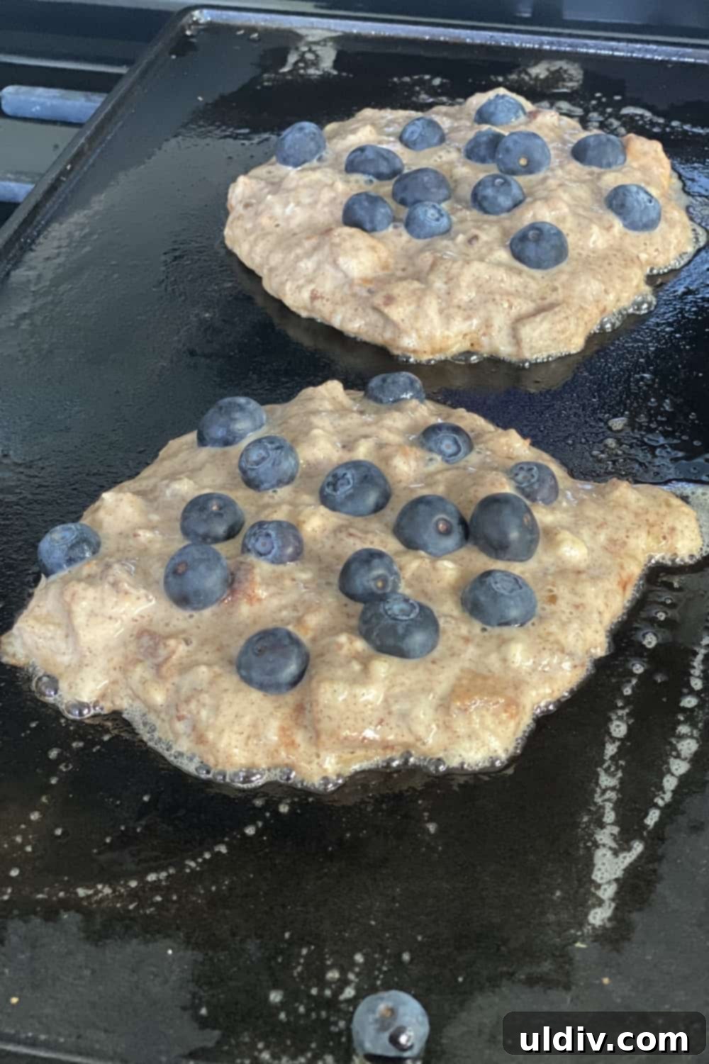 Chef cooking blueberry pancakes on a griddle, showcasing proper technique