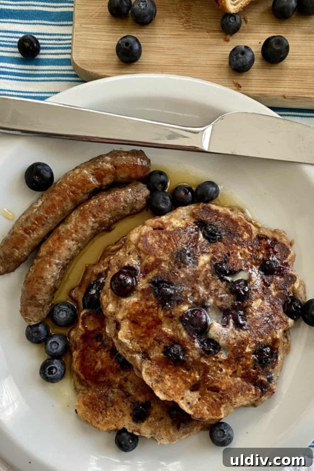 Stack of blueberry bread pudding pancakes served with breakfast sausage