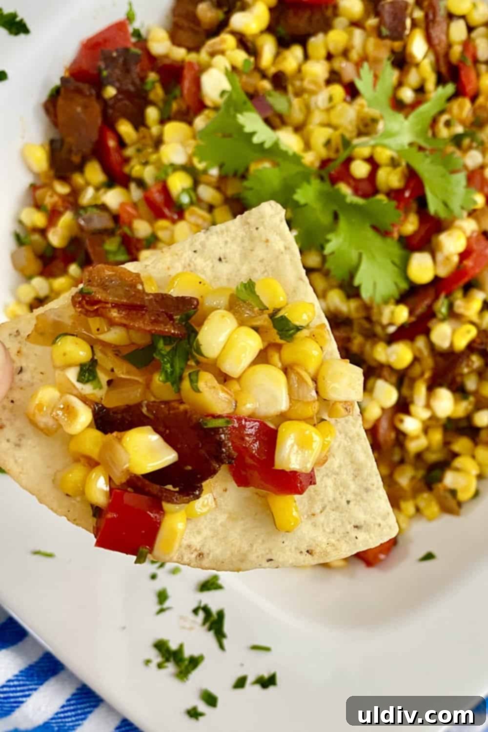 Smoky Bacon Sweet Corn Salad 2 Sweet corn salad on a tortilla chip, showcasing vibrant colors and crispy bacon