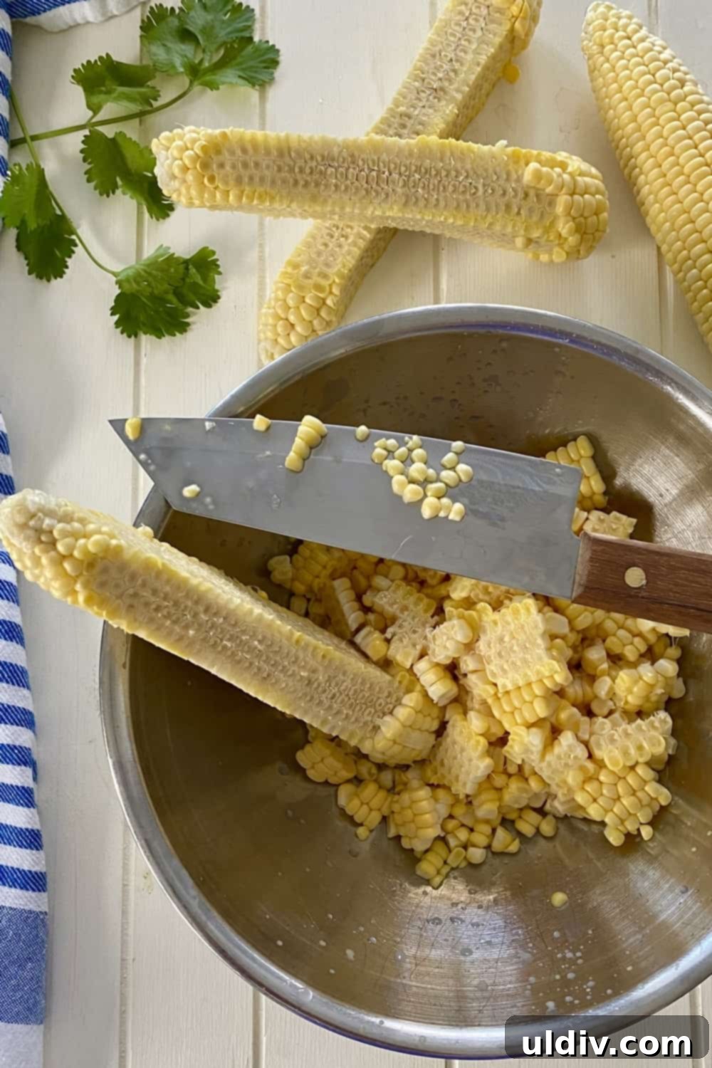 Smoky Bacon Sweet Corn Salad 4 A person demonstrating how to cut corn off the cob into a large bowl to prevent mess