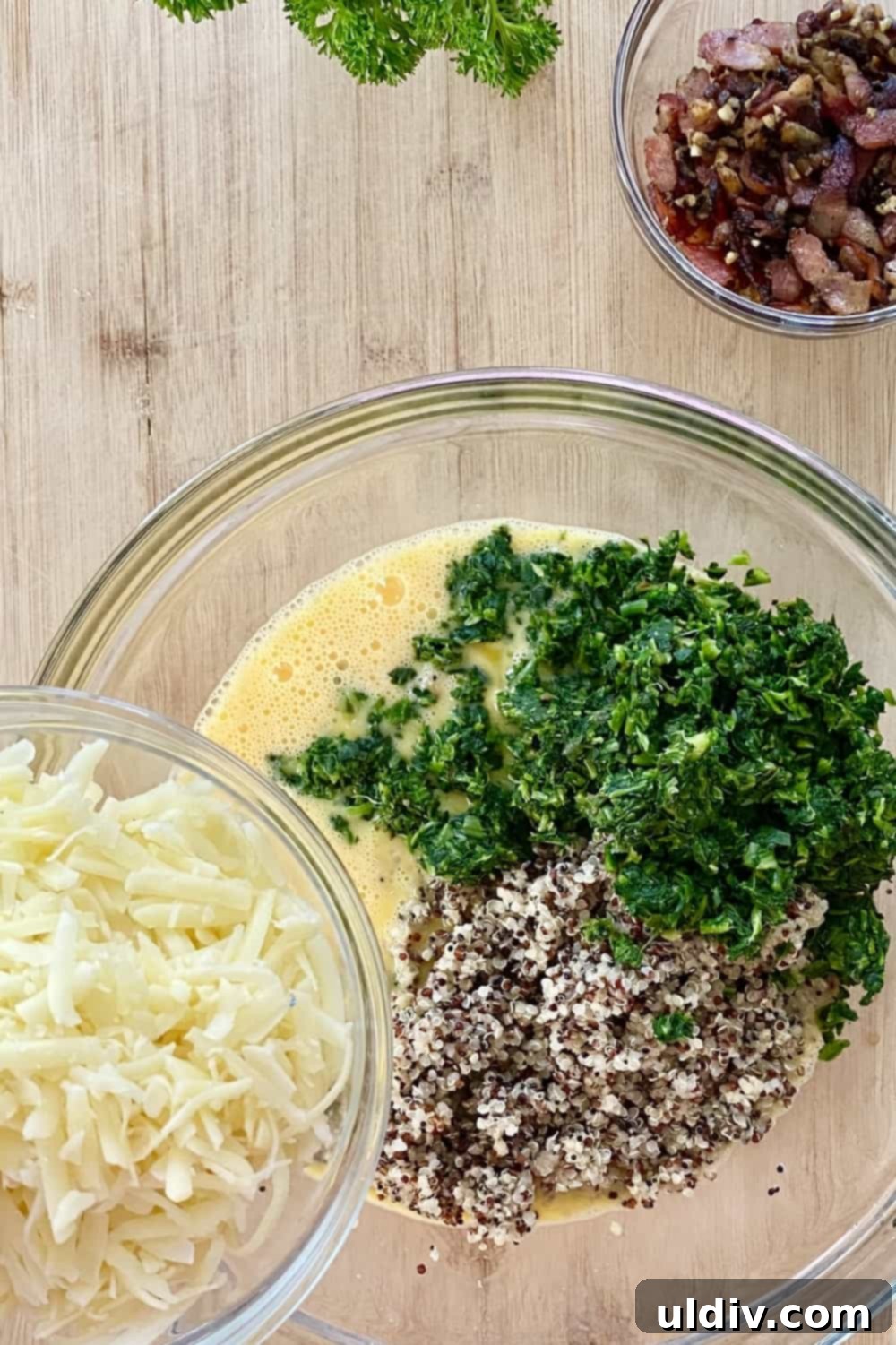 Quinoa Egg Muffins: Breakfast Made Easy 5 A large bowl filled with beaten eggs, with a generous amount of shredded Gruyere and grated Parmesan cheese being added, anticipating the next step of mixing the muffin ingredients.