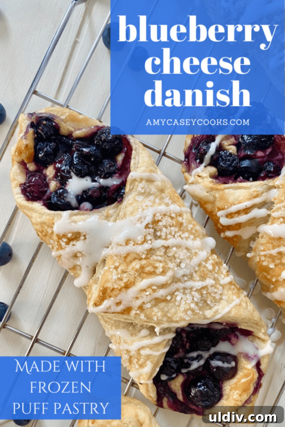 Blueberry Cream Cheese Danish Bliss 10 Two freshly baked blueberry danishes with delicate icing drizzle on a wire cooling rack.