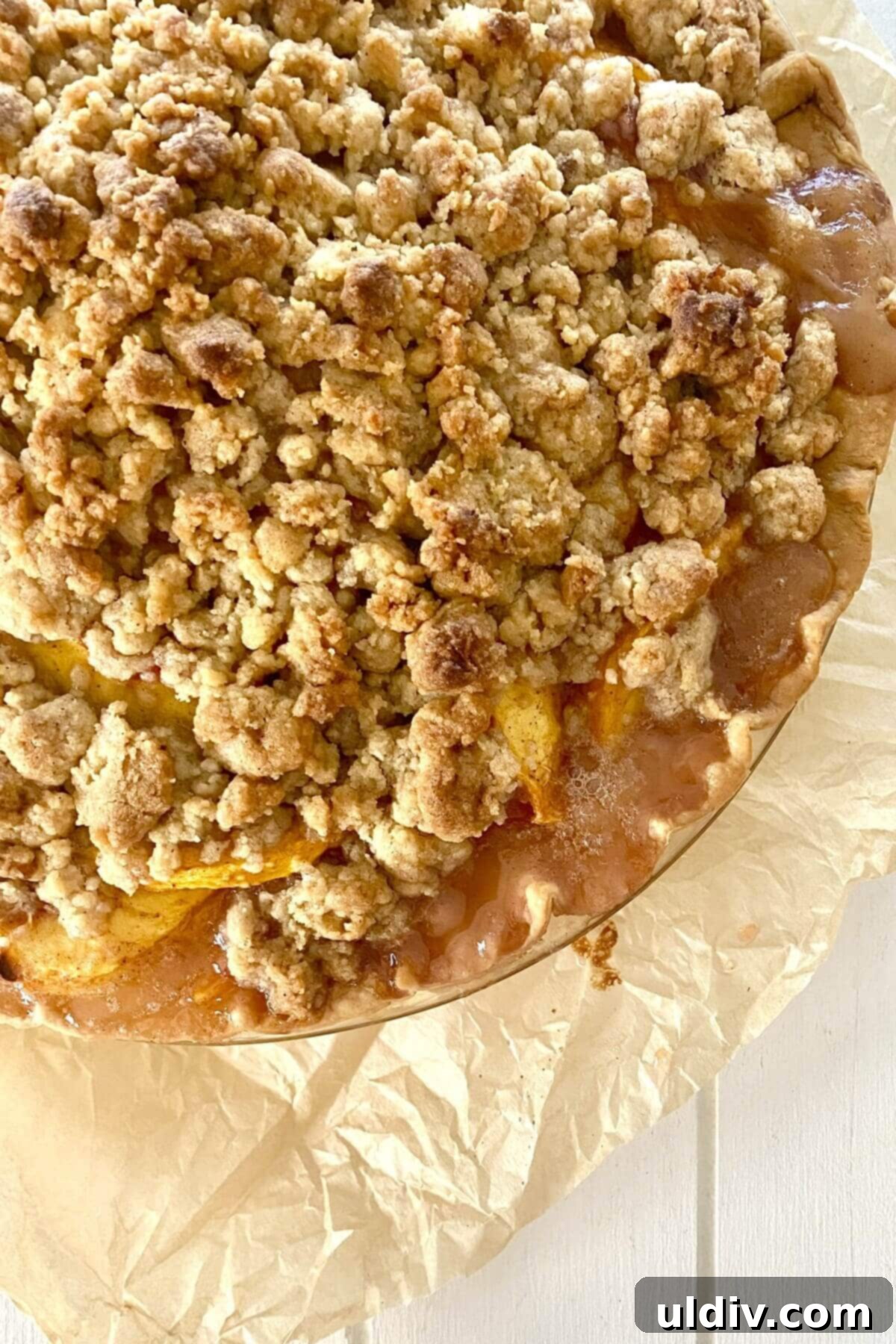 Perfect Peach Crumble Pie 4 A freshly baked peach crumble pie, golden brown and bubbling, resting on parchment paper on a baking sheet, ready to be cooled.