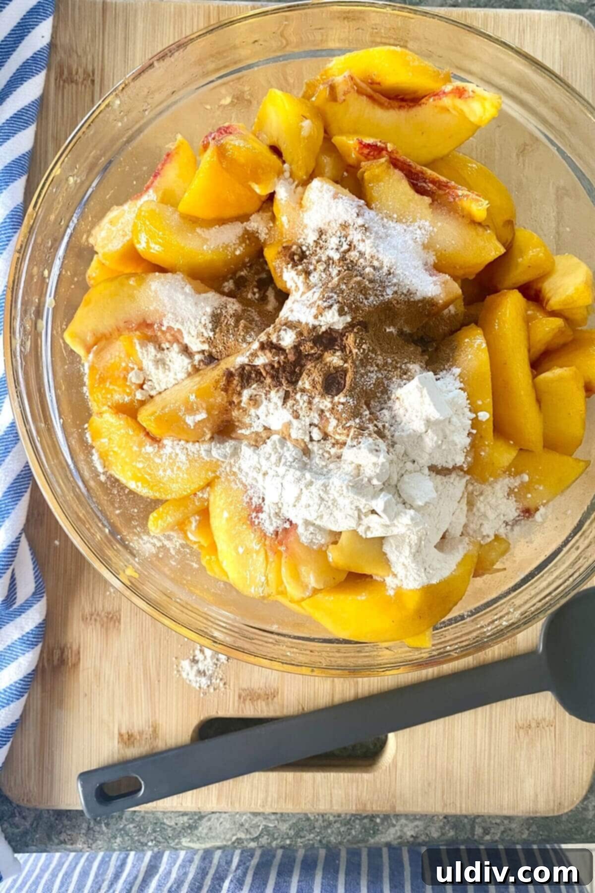 Perfect Peach Crumble Pie 7 A large bowl filled with peeled and sliced peaches, coated in a sweet, spiced mixture, ready for the pie.