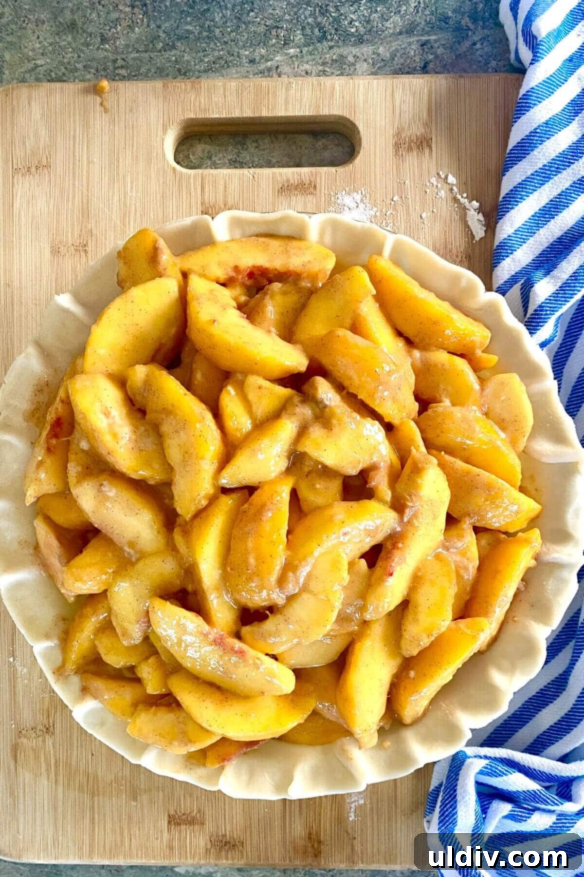 Perfect Peach Crumble Pie 9 An unbaked peach pie with the fruit filling spread evenly over the breadcrumb-lined crust.