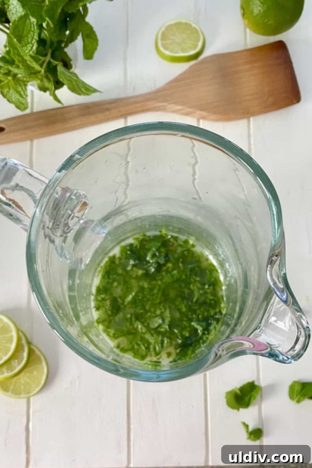 Pitcher Perfect Lime Vodka Fizz 4 Fresh mint leaves being muddled in a pitcher with limeade concentrate.