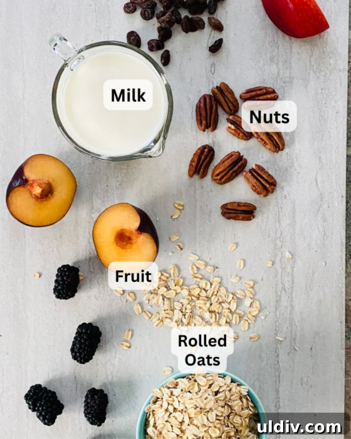 Effortless Overnight Oats 4 A flat lay of fresh ingredients for overnight oats: rolled oats, sliced plums, dark blackberries, a splash of milk, and whole pecans.