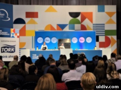 Chef Rick Bayless speaking to an attentive audience about recipes and culinary trends at the 2023 National Restaurant Association Show