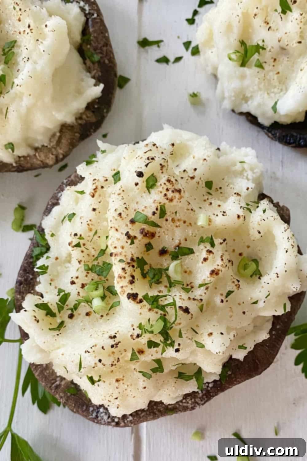 Savory Mashed Potato Portobello Caps 2 A plate of vegetarian mashed potato stuffed mushrooms, garnished with fresh herbs.