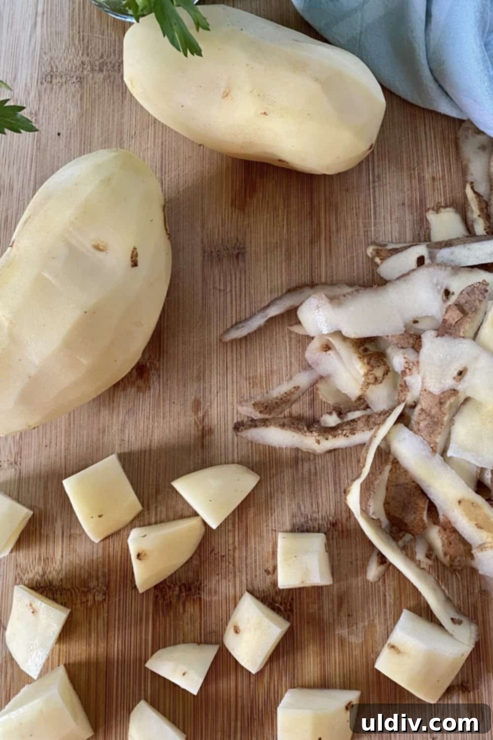 Savory Mashed Potato Portobello Caps 6 Peeled and cubed potatoes alongside potato peels on a cutting board, ready for cooking.