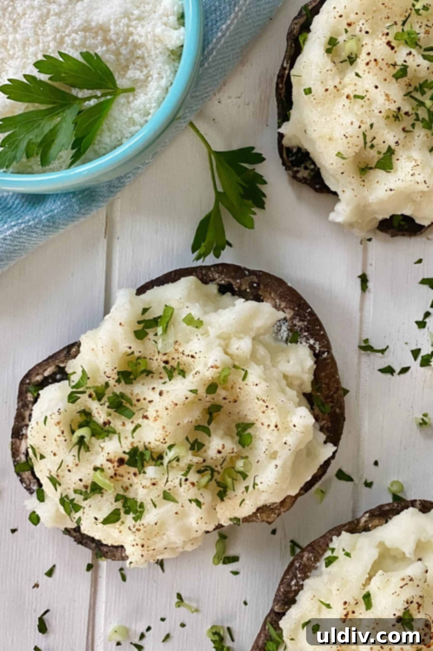 Savory Mashed Potato Portobello Caps 10 A bowl of grated Parmesan cheese next to two perfectly stuffed portobello mushroom caps.