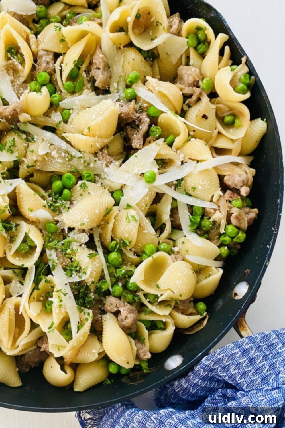 30-Minute Sausage and Pea Pasta 2 A large sauté pan of pasta and peas and topped with Parmesan cheese.