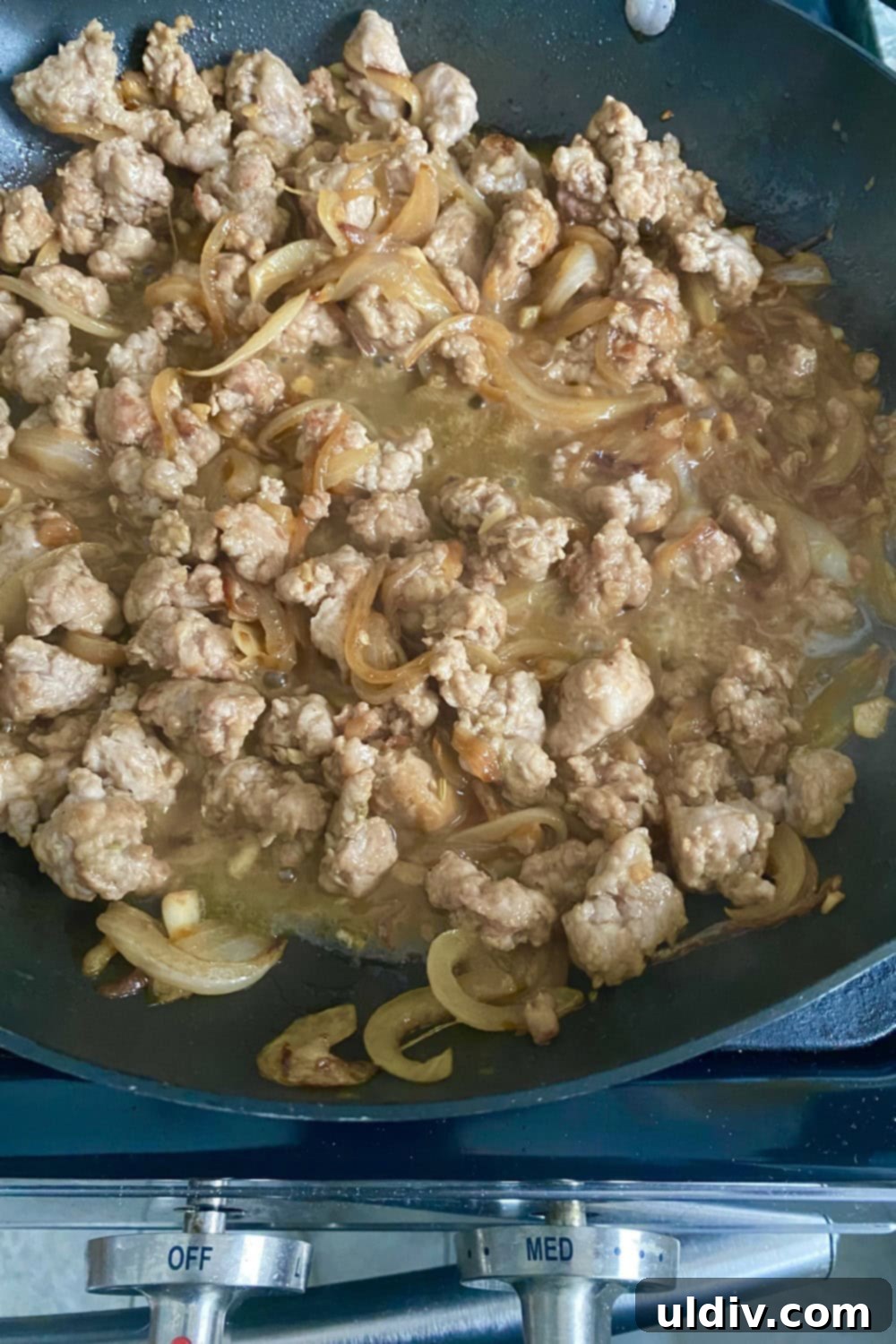 30-Minute Sausage and Pea Pasta 5 Cooked and crumbled sausage with onions and stock in a pan.