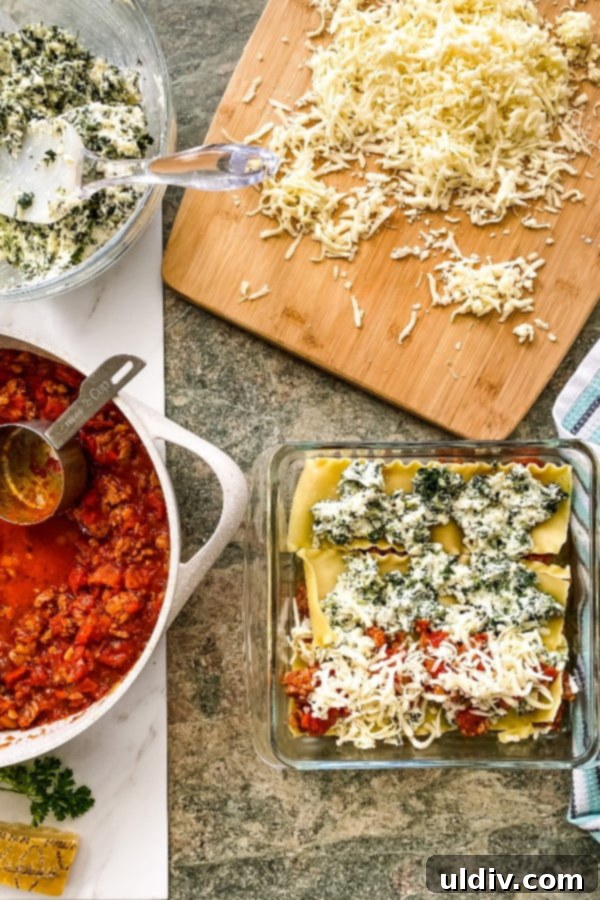 Hearty Spinach and Sausage Lasagna 3 assembling a lasagna with layers of pasta, cheese, and Italian sausage tomato sauce in a baking dish