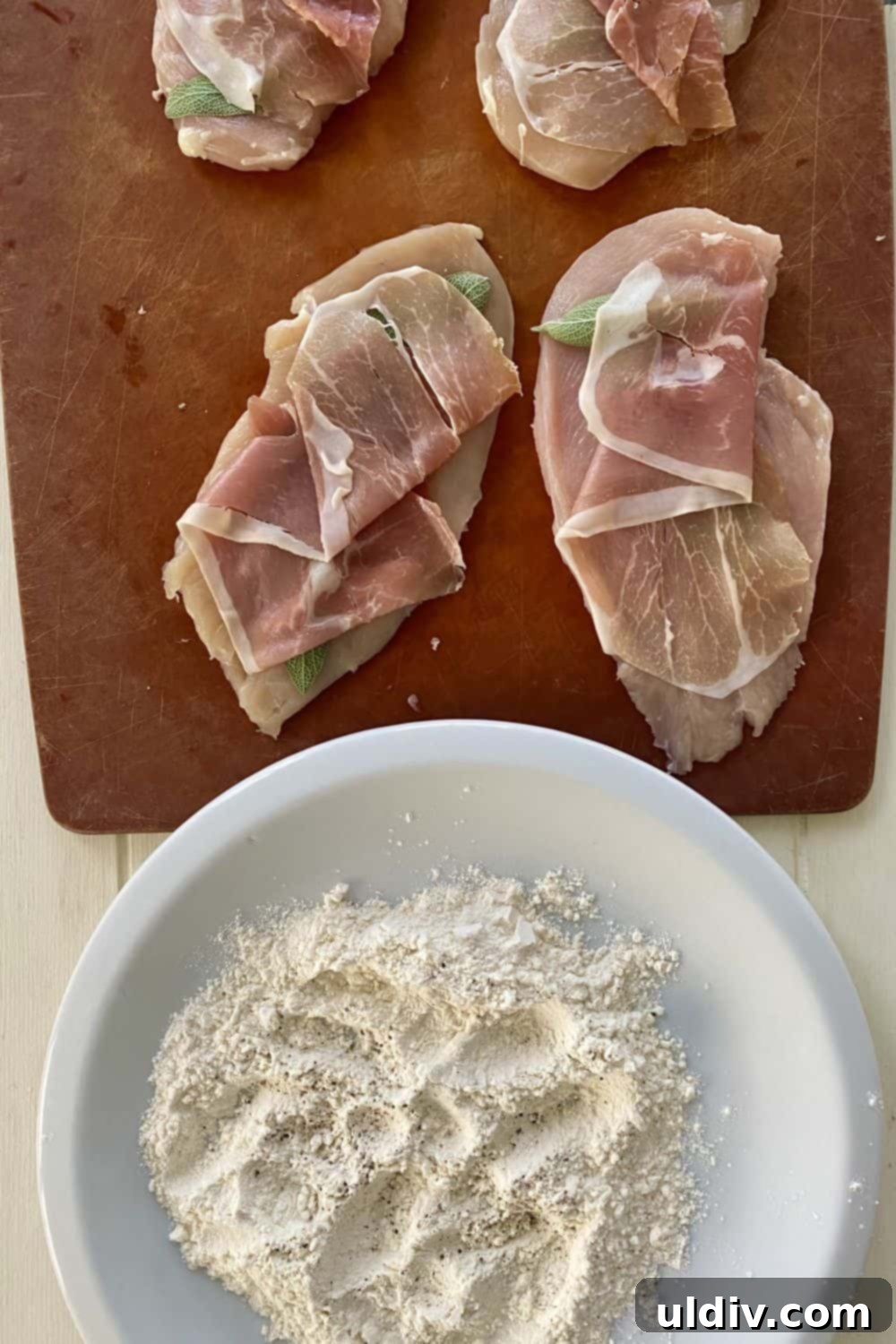 Marsala Mushroom Chicken with Prosciutto and Sage 4 Thin chicken cutlets, each carefully topped with vibrant fresh sage leaves and a slice of delicate prosciutto, laid out and ready for the next step of dredging and cooking.