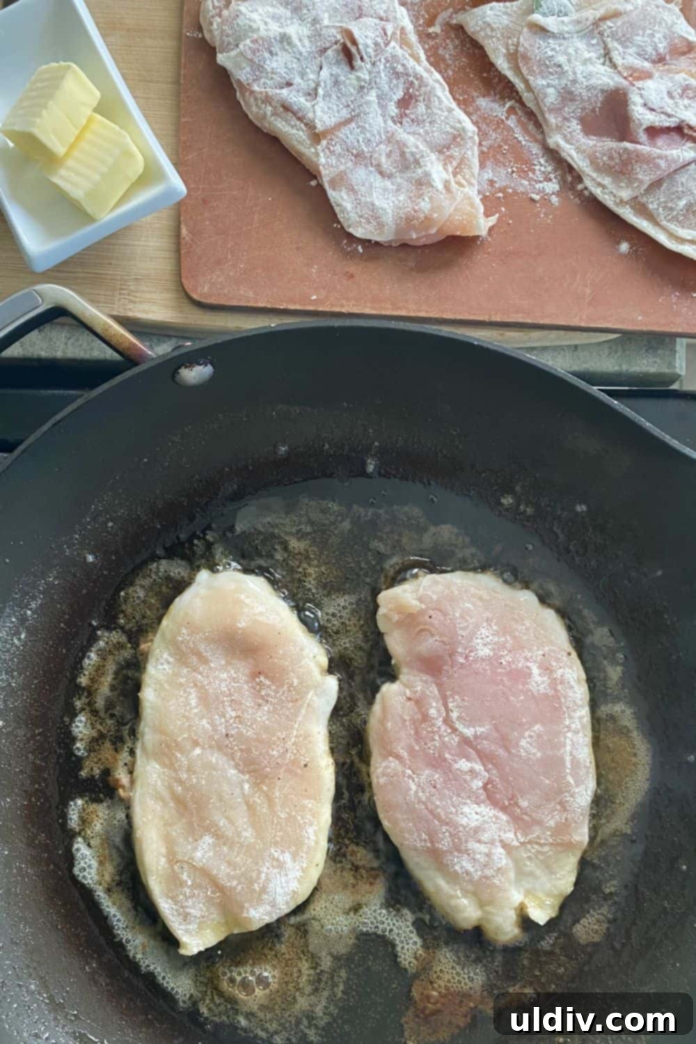 Prosciuttolu, Taze Adaçayı ve Marsala Mantar Soslu Tavuk 5 A large sauté pan with several chicken cutlets cooking, showing the golden-brown crust forming on the prosciutto side.