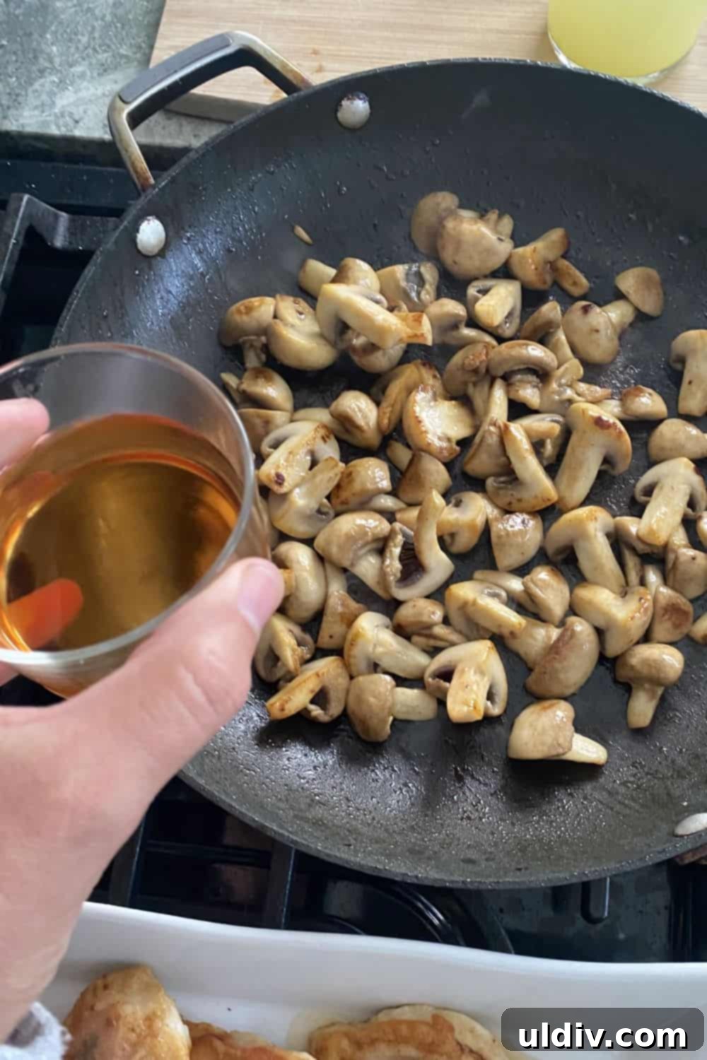 Marsala Mushroom Chicken with Prosciutto and Sage 6 Marsala wine being carefully poured into a sauté pan filled with browned mushrooms, initiating the crucial deglazing process for building the rich sauce.